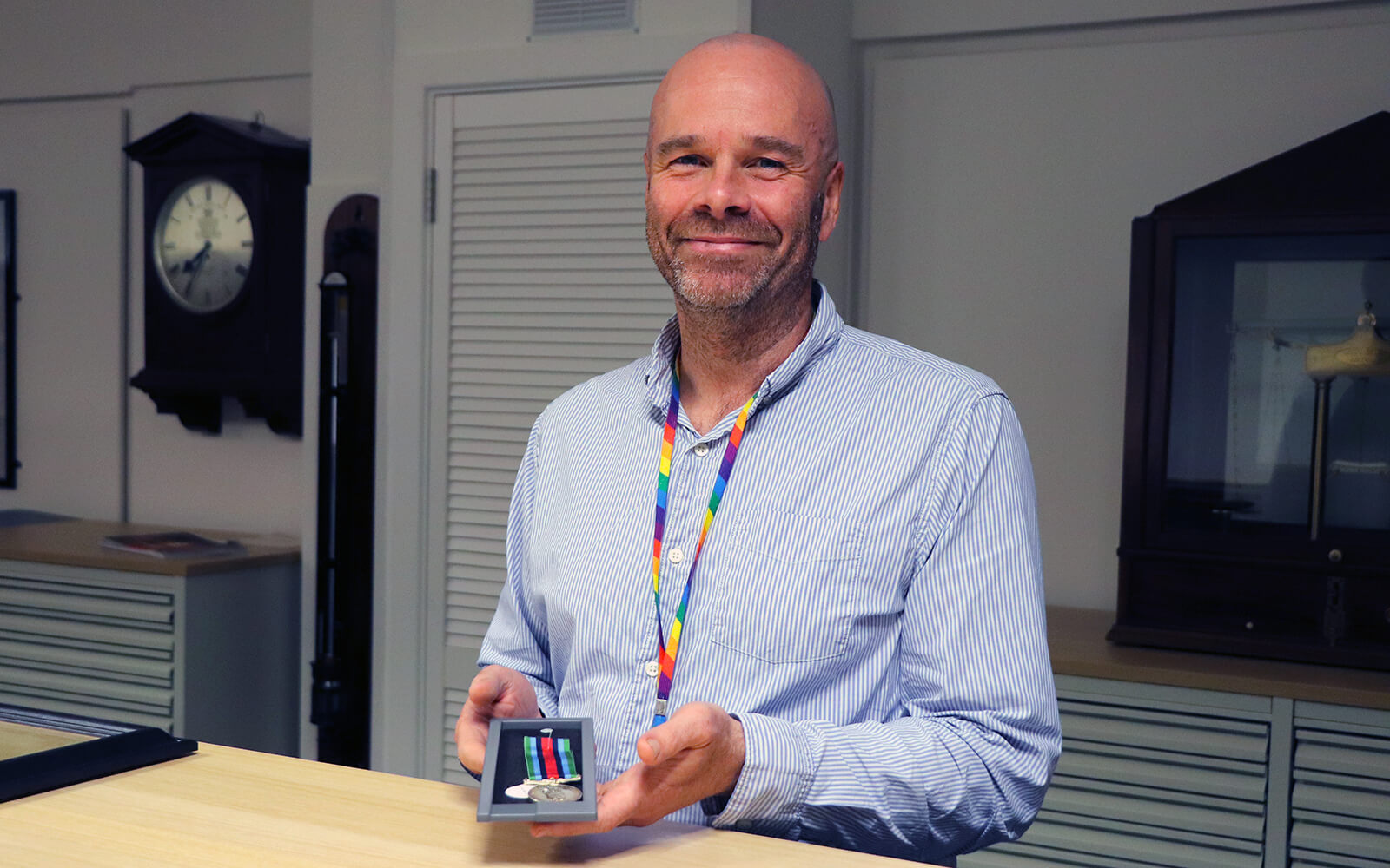 Richard Phelps standing behind a desk holding a medal