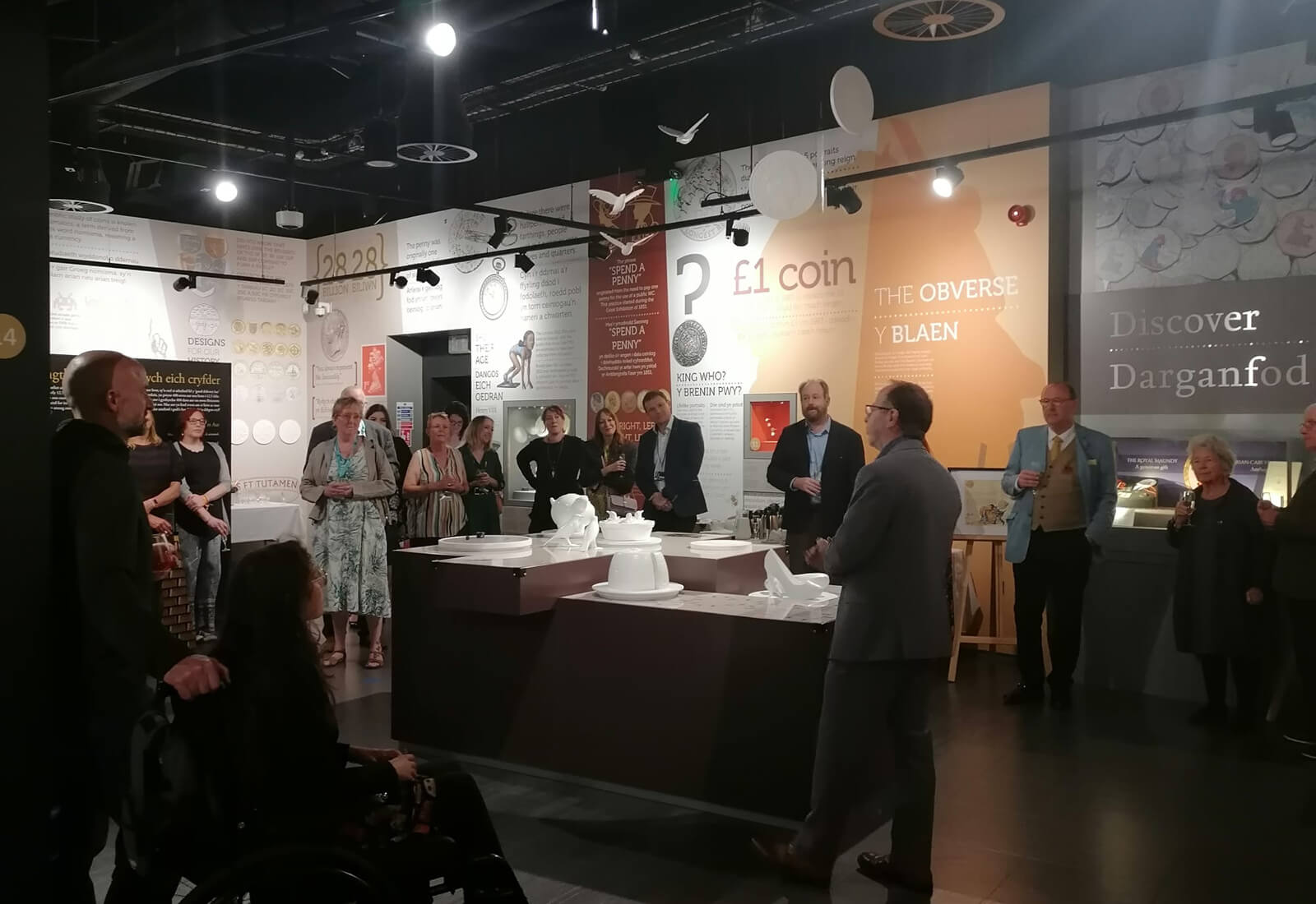 People standing in the galleries of the Royal Mint Experience listening to a talk by Museum Director Kevin Clancy
