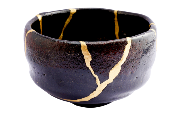 A Japanese Kintsugi bowl. The bowl is black with gold paint running along the cracks.