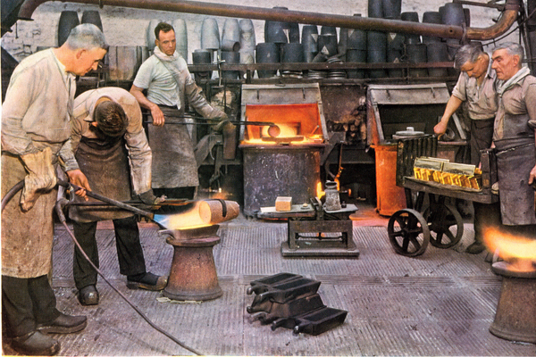 Men working in a gold melting room. There are gold bars on a trolley behind them.