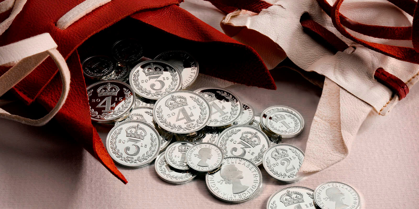 2015 dated silver Maundy Money spilling out of re and white purses