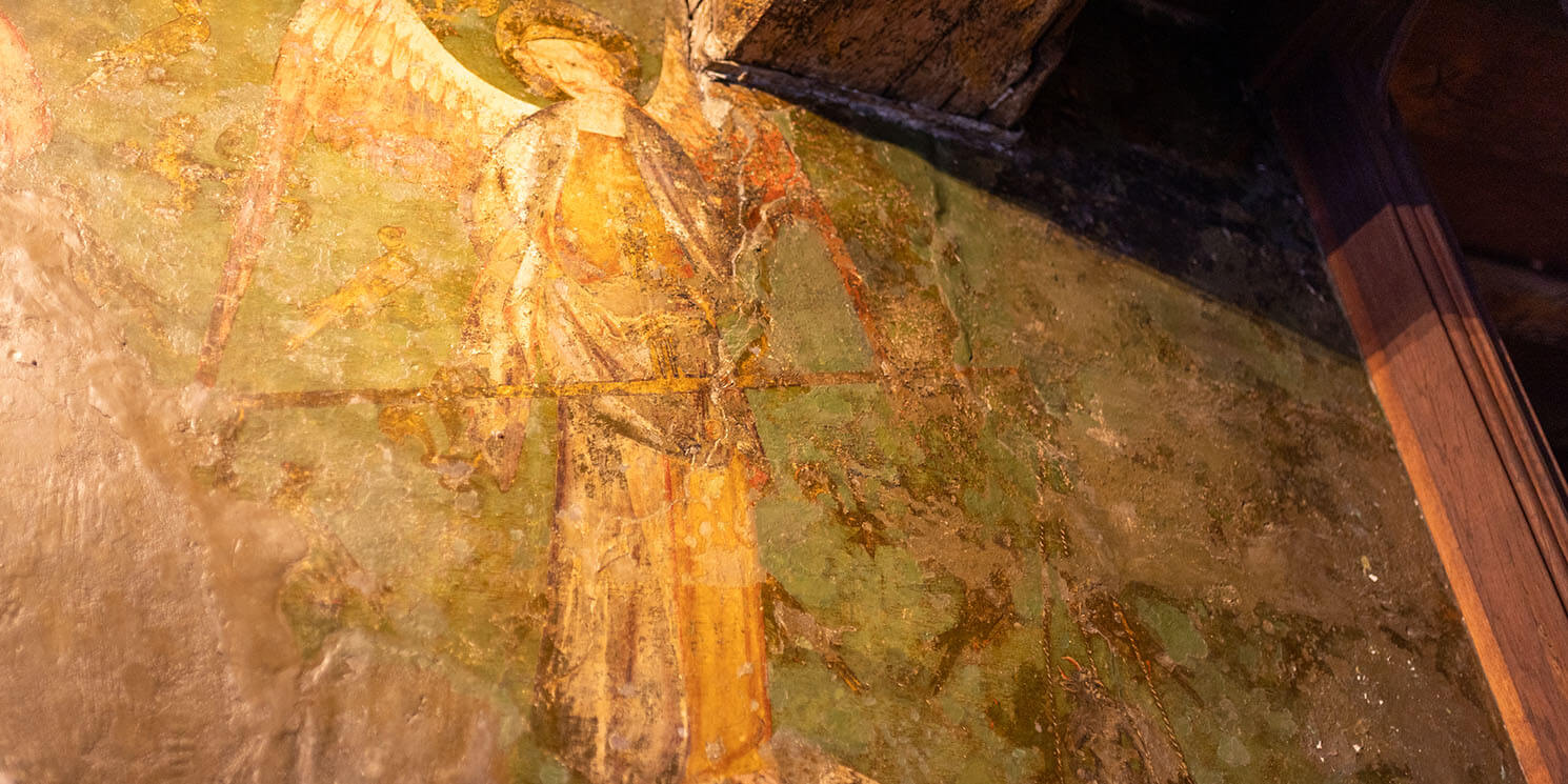 Archangel Michael featured on the wall painting he holds a set of golden scales with a devil on one side