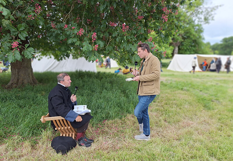 Chris Barker interviewing sealed knot member Jeremy Burrows. They are in a field under a tree and Jeremy Burrows is in Civil War costume
