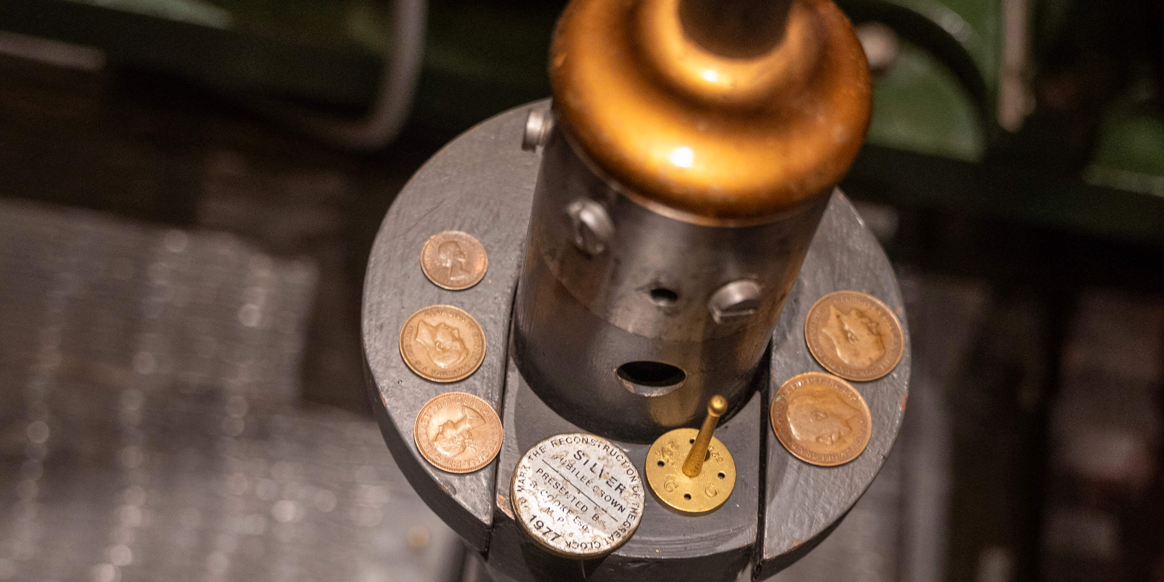 A collection of coins laying on a shelf on the pendulum of Big Ben.