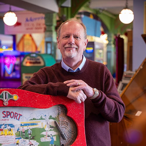Peter Williamson standing in front of a brightly coloured machine in Williamson's Penny Arcade attraction